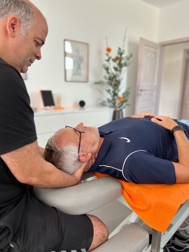 Physiotherapeut behandelt den Nacken eines liegenden Patienten in der Physiozentrale Angelmodde