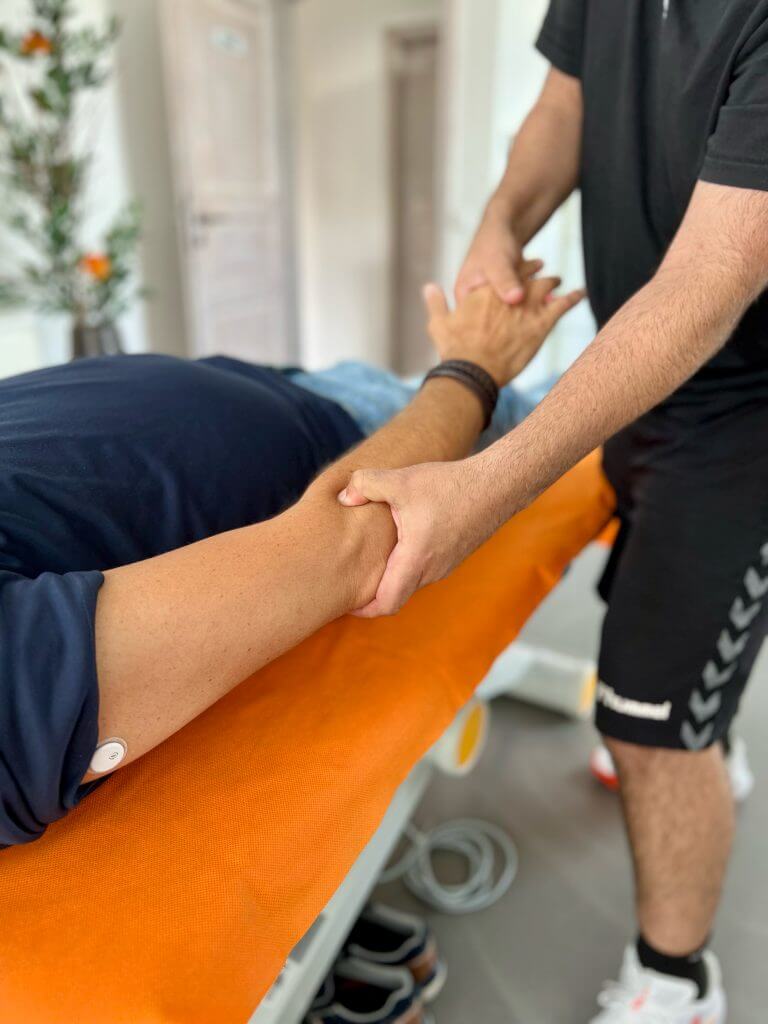 Physiotherapeut behandelt den Arm eines Patienten auf der Behandlungsliege in der Physiozentrale Angelmodde